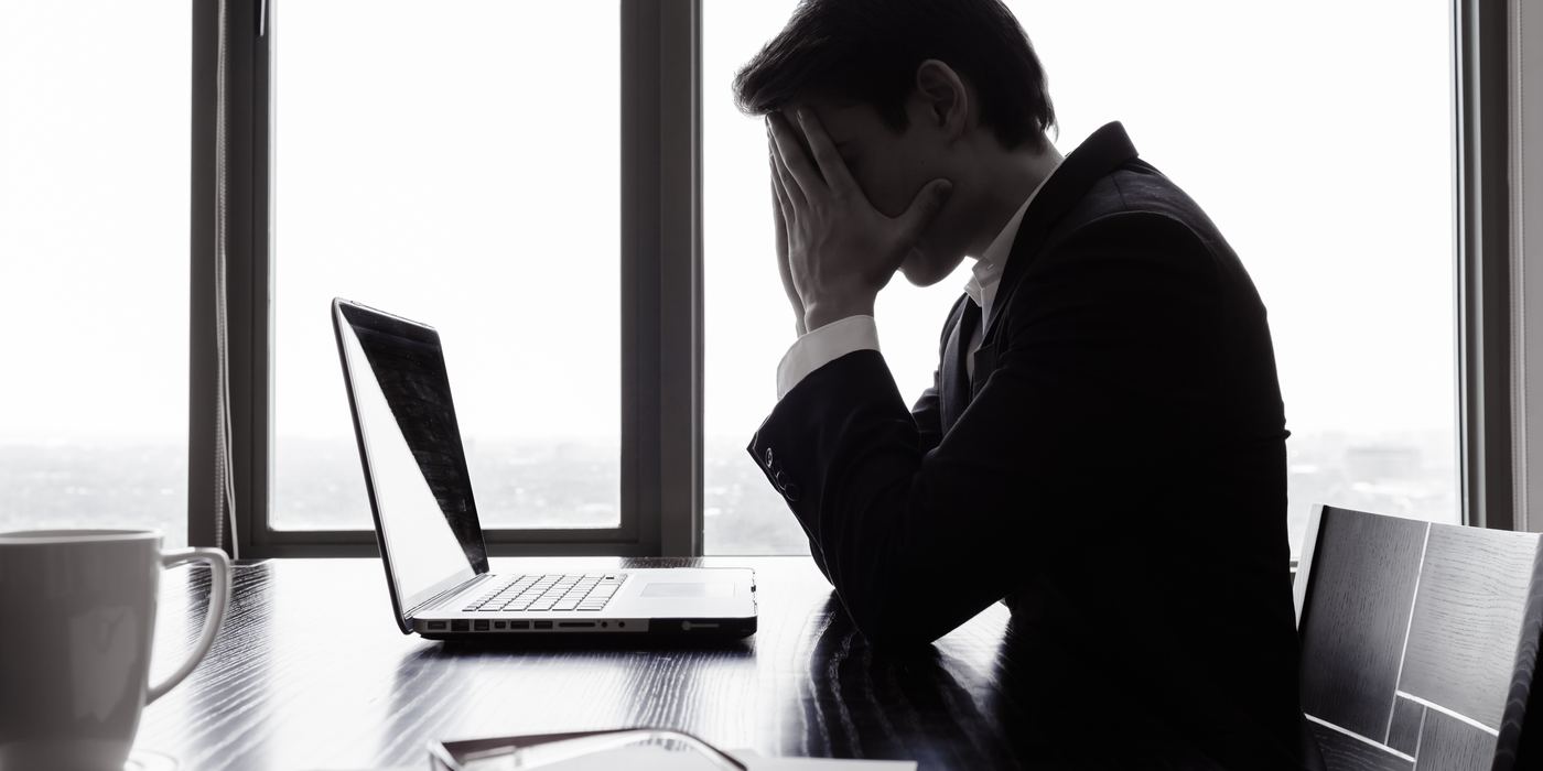 机に向かい、頭を抱える社長